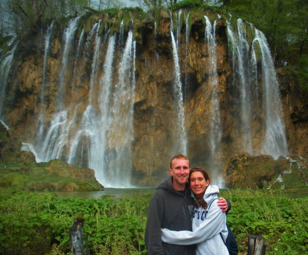 A couple standing in front of a waterfall at Plitvice Lakes National Park