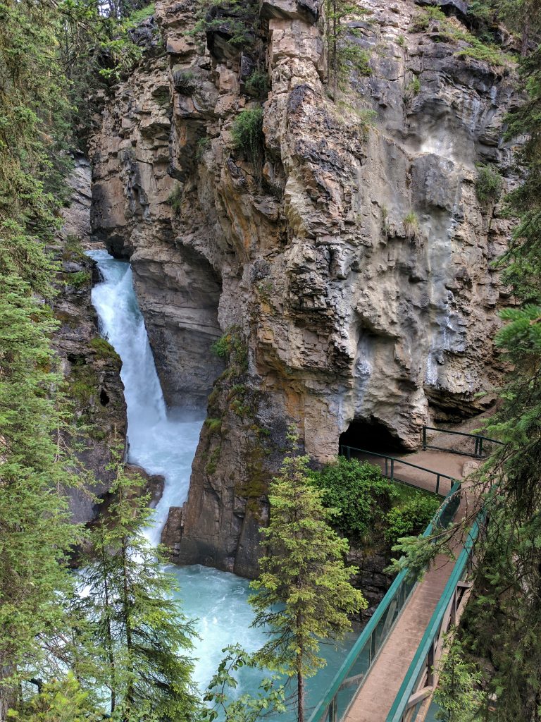 A bridge leading to a cave beside a waterfall at Johnston Canyon