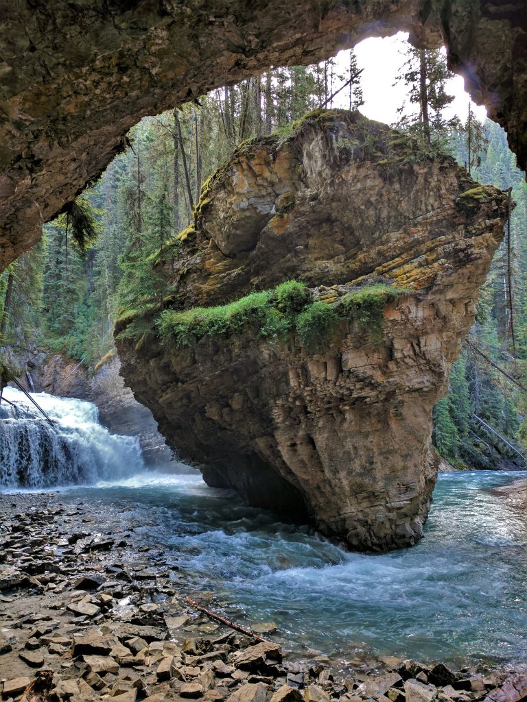 A massive rock near a small waterfall in Johnston Canyon