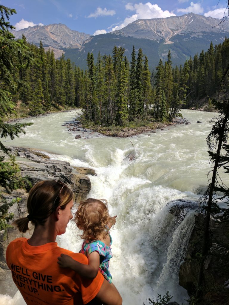 A woman holding a small child looking at Sunwapta Falls