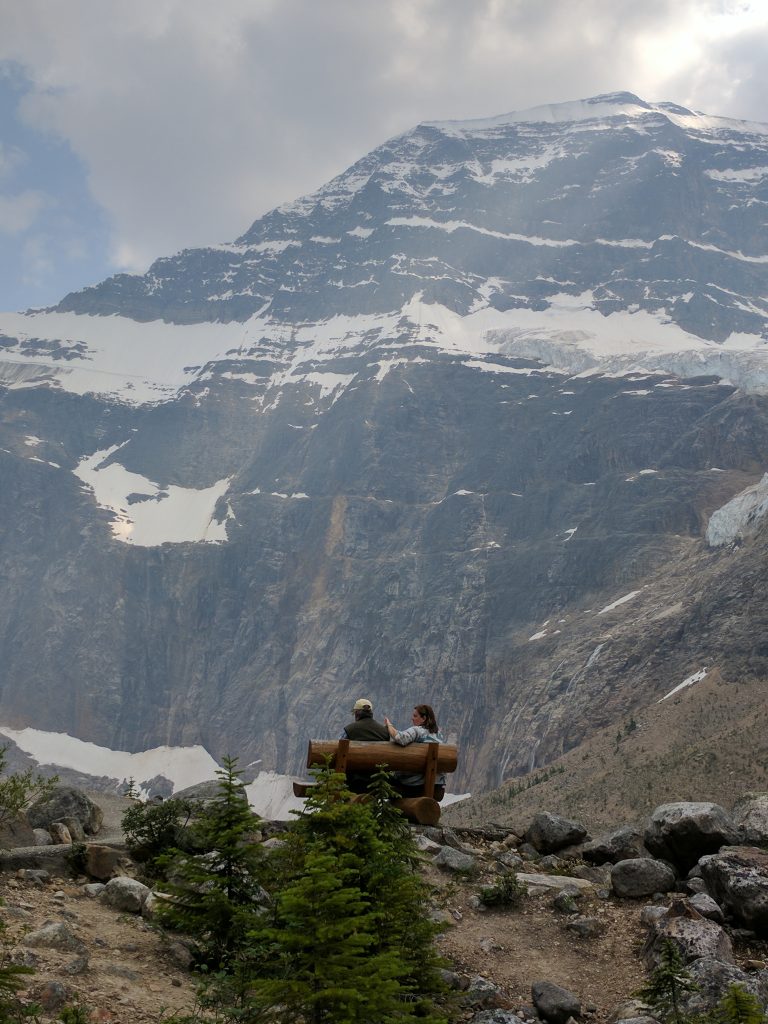 A couple sitting on a bench with Mount Edith Cavell looming large in the background