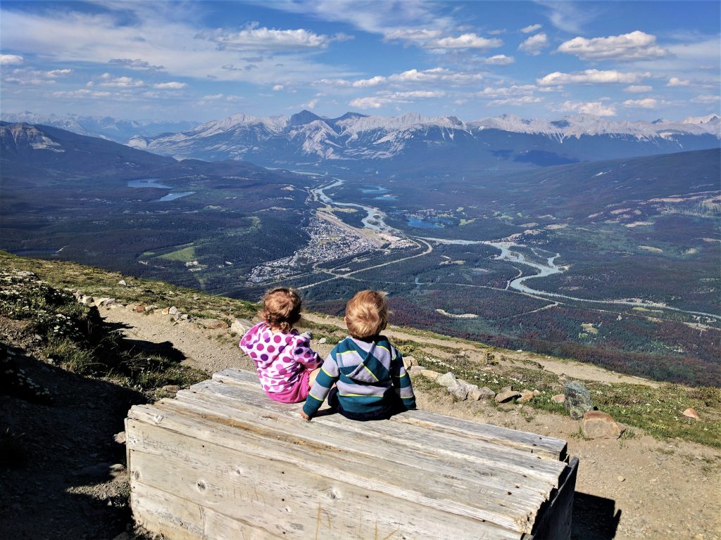 Young children sitting on a bench overlooking Jasper in the Canadian Rockies