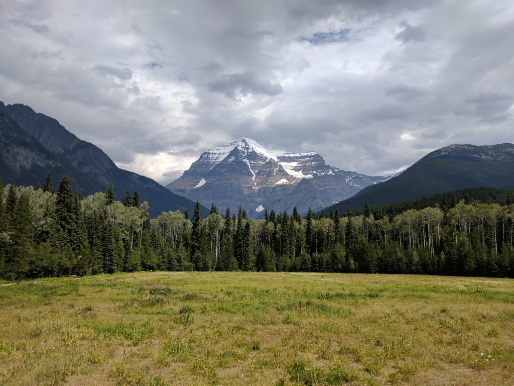 Mount Robson framed by rolling hills on a cloudy day