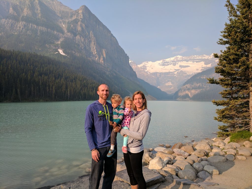 A family with young children at Lake Louise with mountains and a glacier in the background