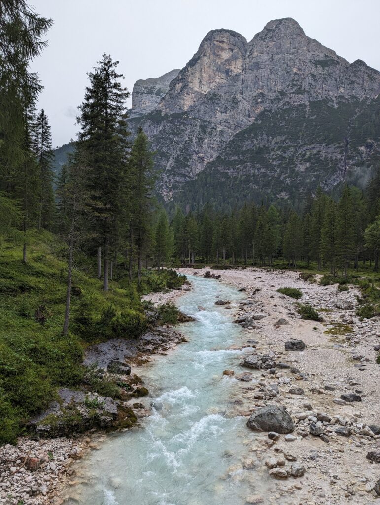 A glacial stream with a looming mountain in the background in the Dolomites