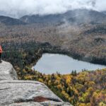 A hiker on the edge of a cliff overlooking Heart Lake, near Mount Jo