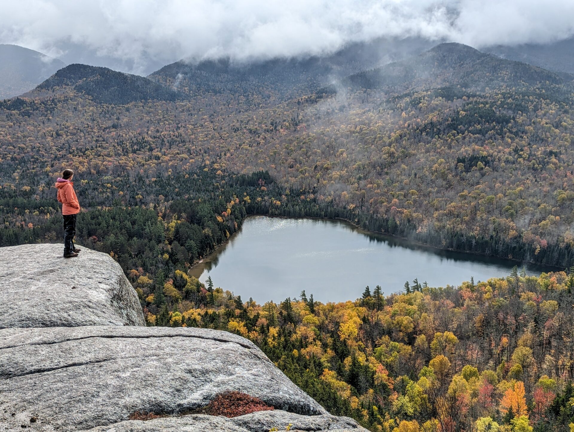 A hiker on the edge of a cliff overlooking Heart Lake, near Mount Jo