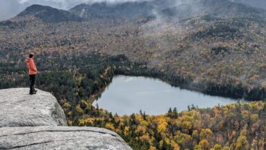 A hiker on the edge of a cliff overlooking Heart Lake, near Mount Jo