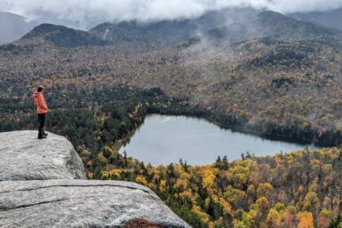 A hiker on the edge of a cliff overlooking Heart Lake, near Mount Jo