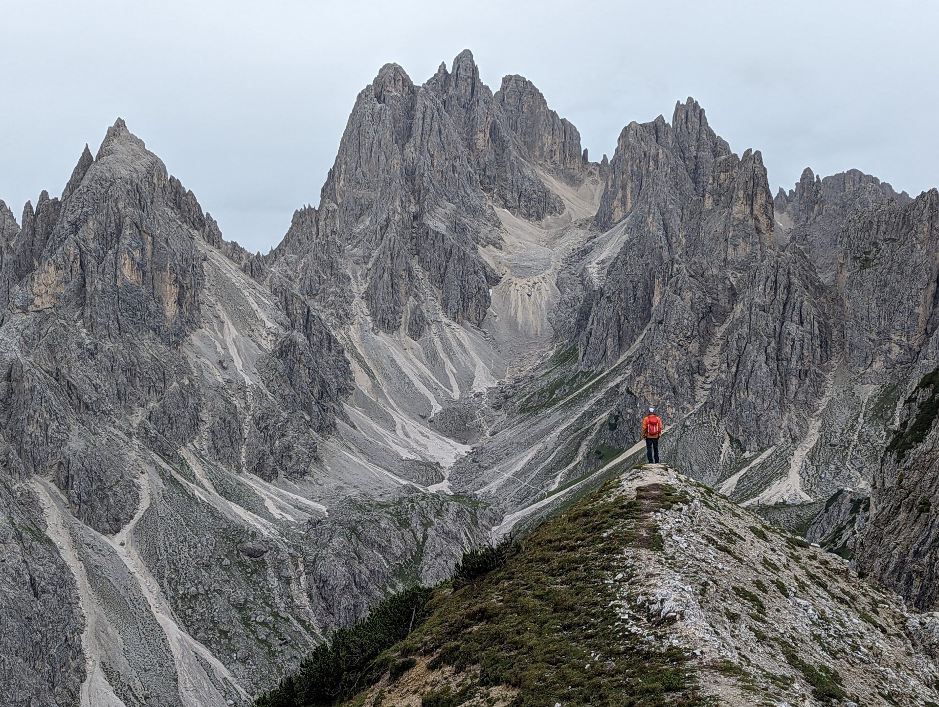 A hiker standing on a point looking at the jagged mountains of Cadini di Misurina