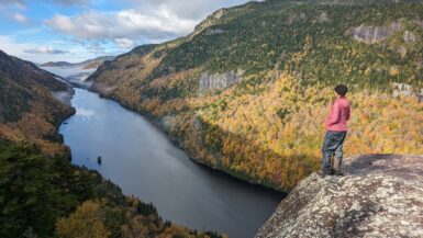 A hiker standing on the edge of Fish Hawk Cliffs in the Adirondacks