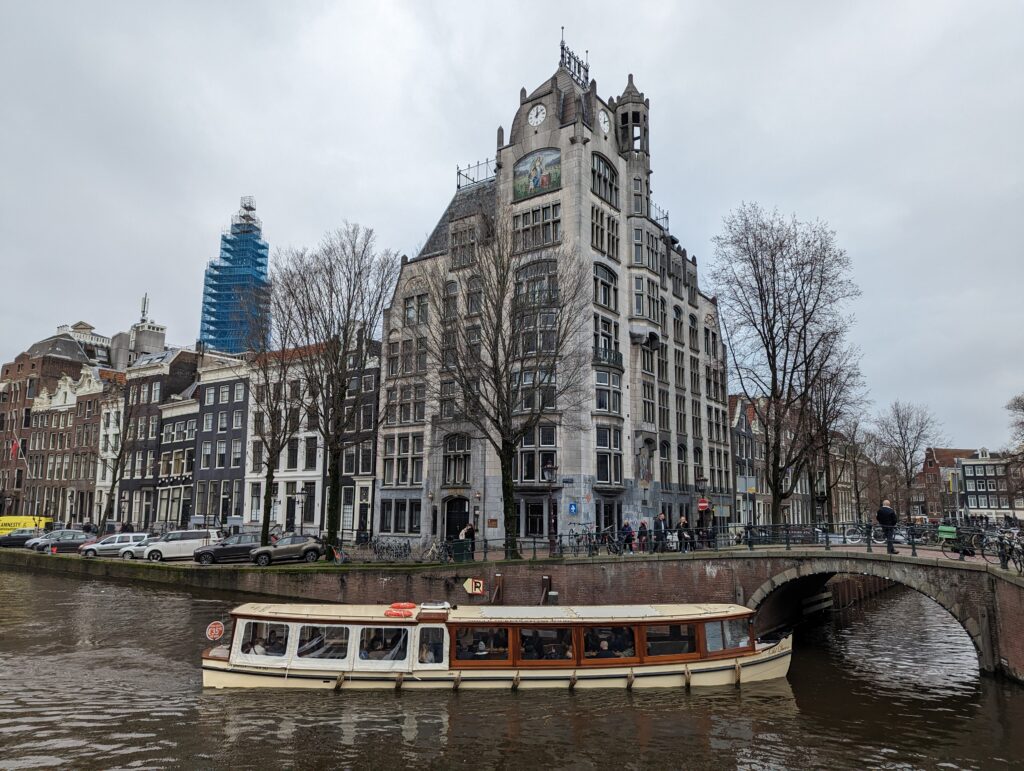 A boat in a canal going past a large building in Amsterdam