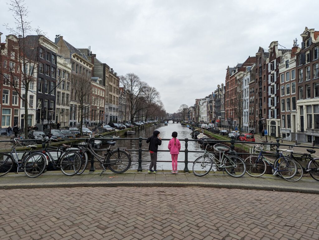 Children surrounded by bicycles standing in front of a canal in Amsterdam