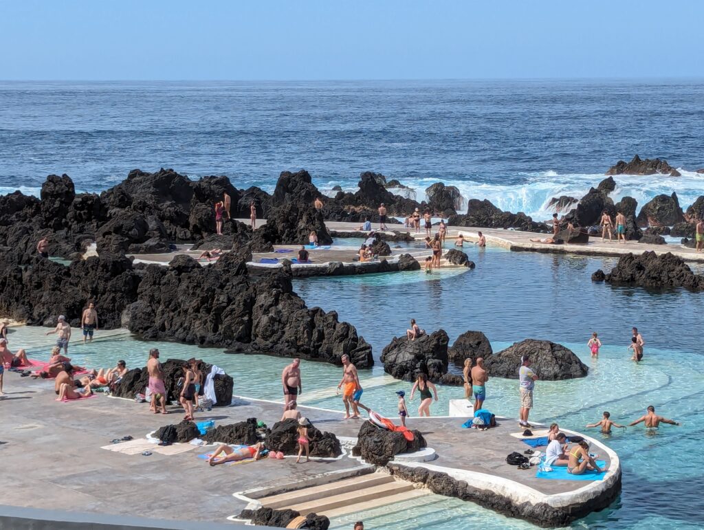 Many people around pools built among volcanic rocks at Porto Moniz, Madeira