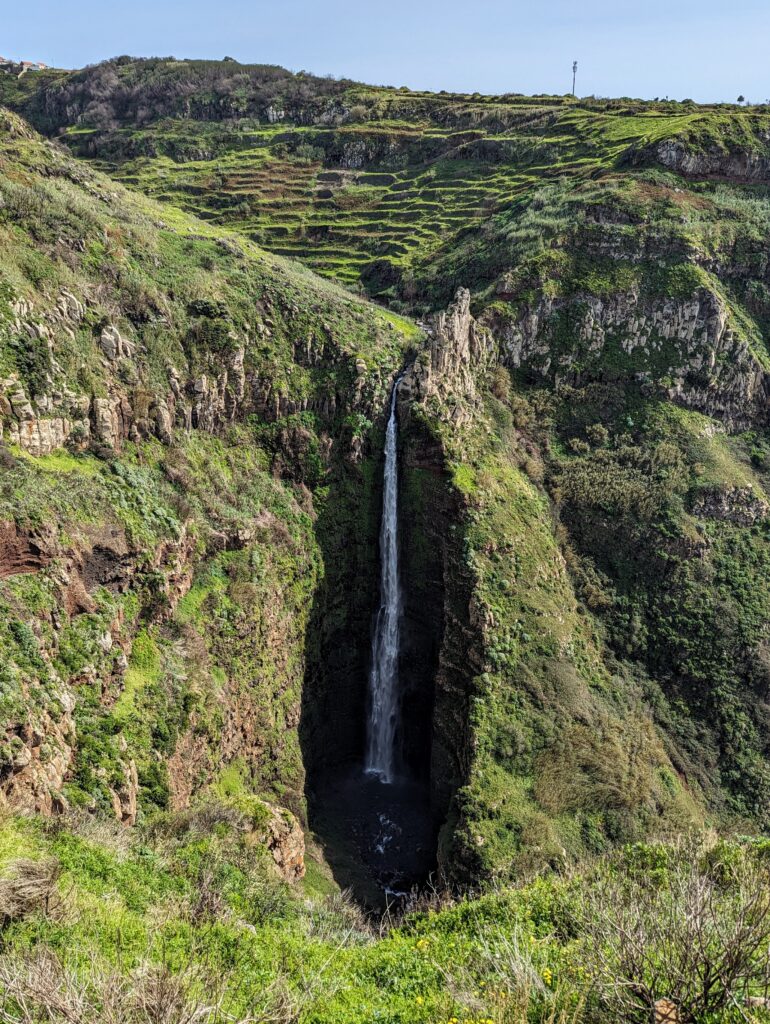 A large waterfall in a shadowed bowl at Miradouro da Garganta Funda in Madeira