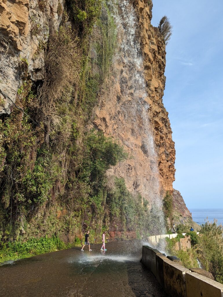 The Cascata dos Anjos waterfall falling directly on the road in Madeira