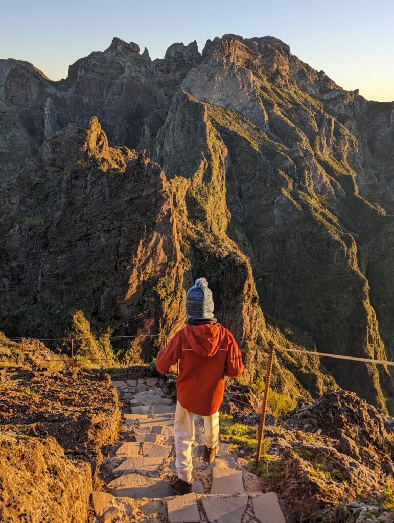 A boy walking on a stone path with jagged mountains in the background on Madeira