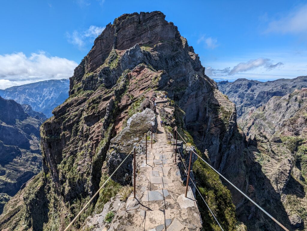 A narrow stone path with guardrails leading to a large mountain peak on Madeira
