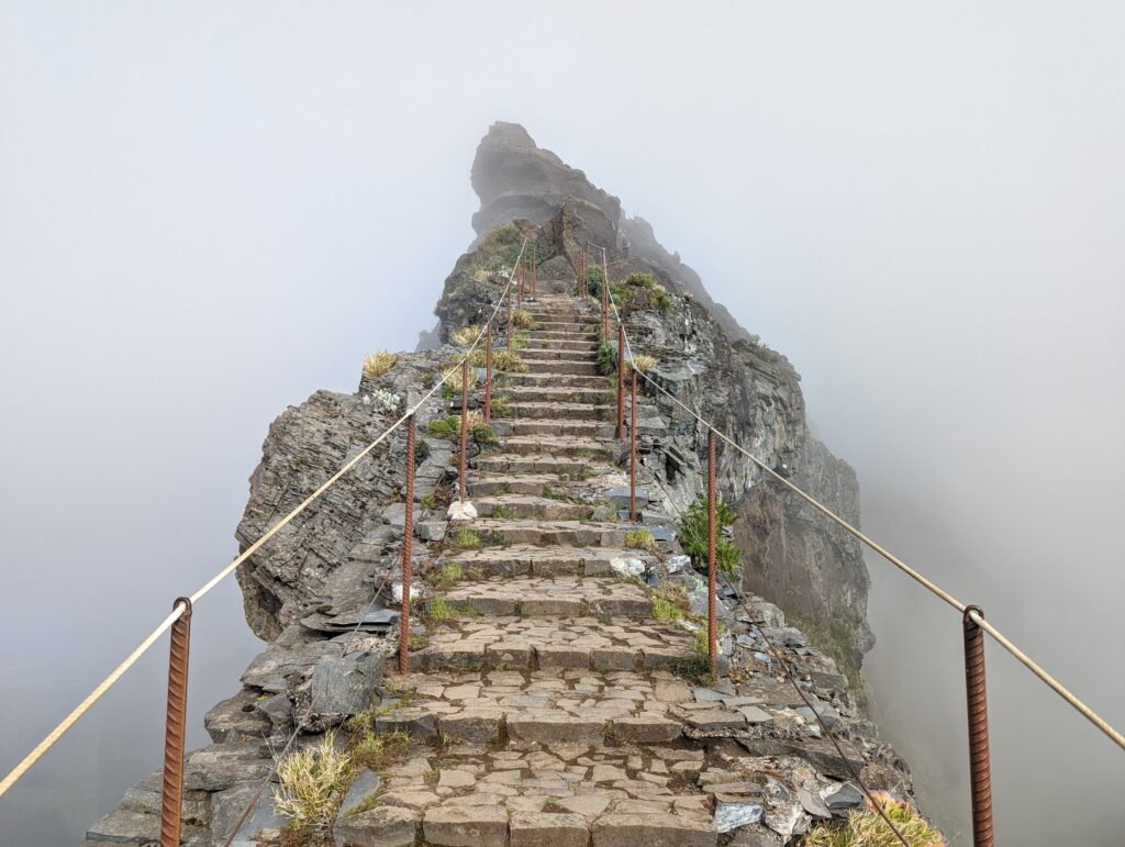 A staircase with guardrails on Madeira leading up to what seems to be the sky, as the whole area is covered in fog