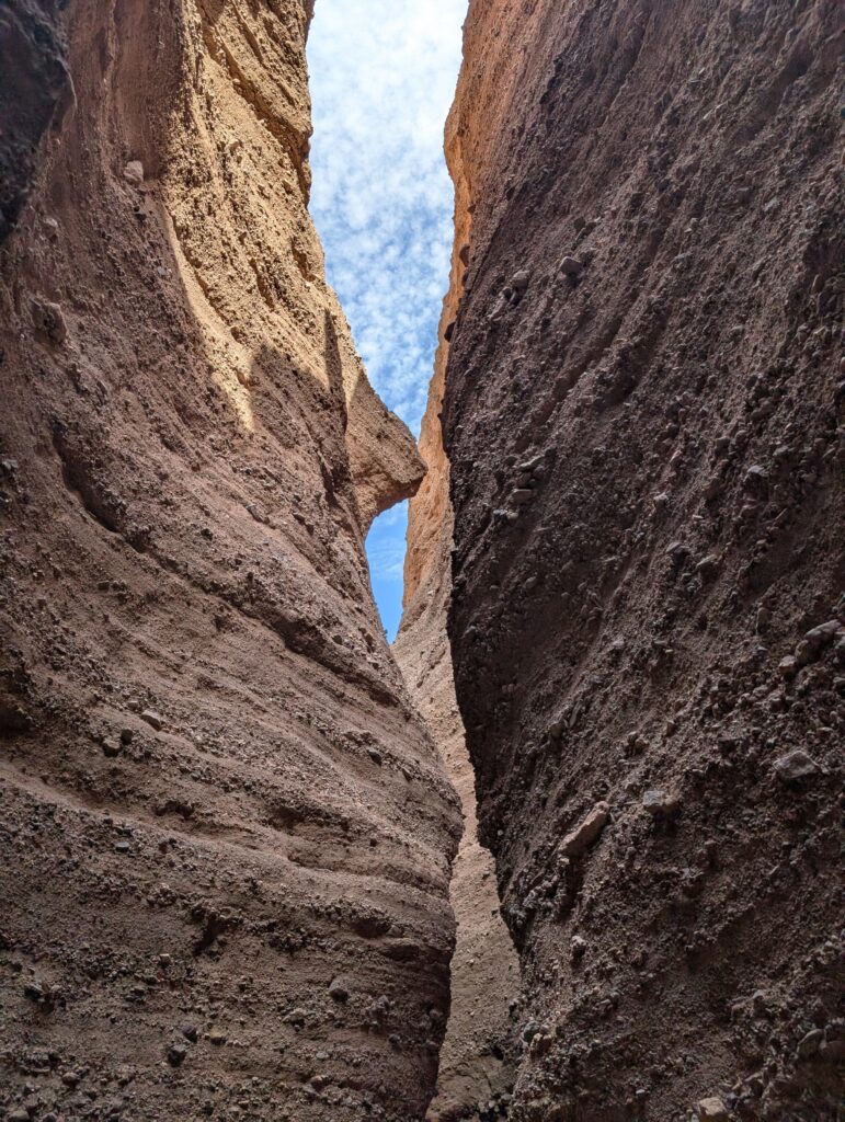 A view looking up at the sky through narrow rock cliffs