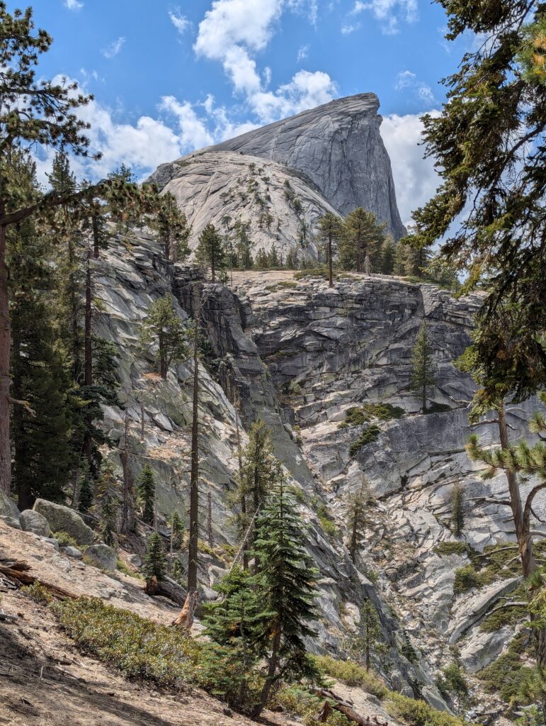 Half Dome and the surrounding granite rocks with a couple trees on the sides and foreground