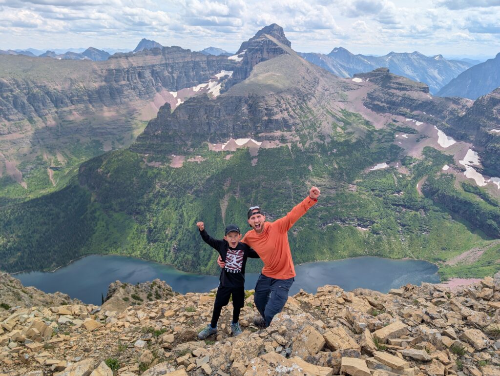 A father and son with excited faces at the summit of Mount Helen in Glacier National Park