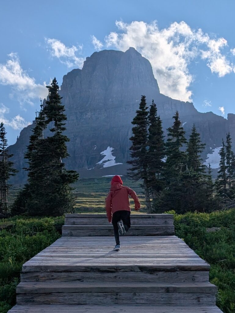 A young boy running on a wooden platform towards a mountain