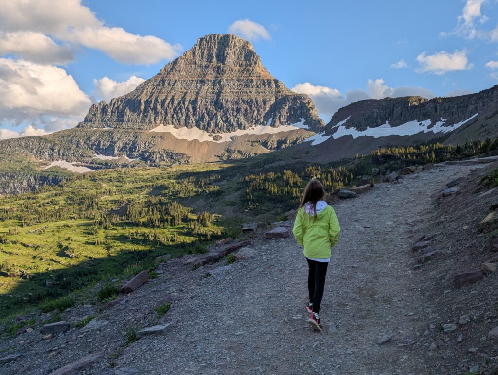 A young girl walking along a stone path with mountains in the background