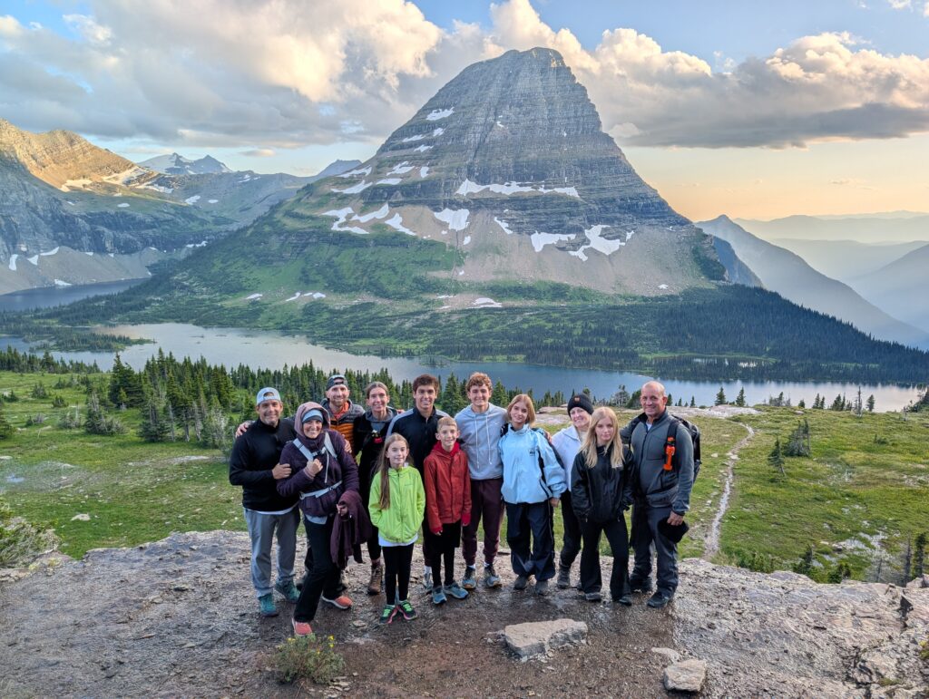 A group of people standing in front of a pyramid-shaped mountain at Hidden Lake Overlook