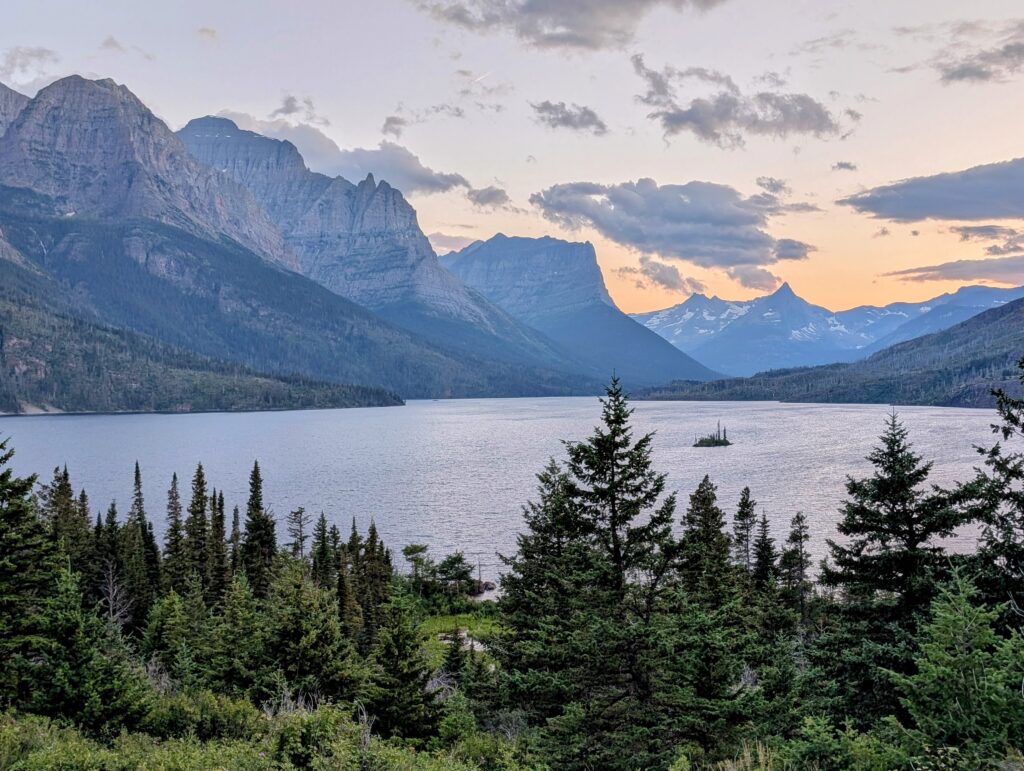 Wild Goose Island in Glacier National Park in the middle of a lake with mountains in the background and trees in the foreground