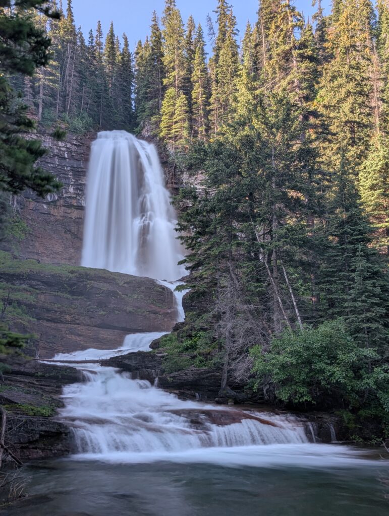 Virginia Falls in Glacier National Park flowing in several stages surrounded by trees