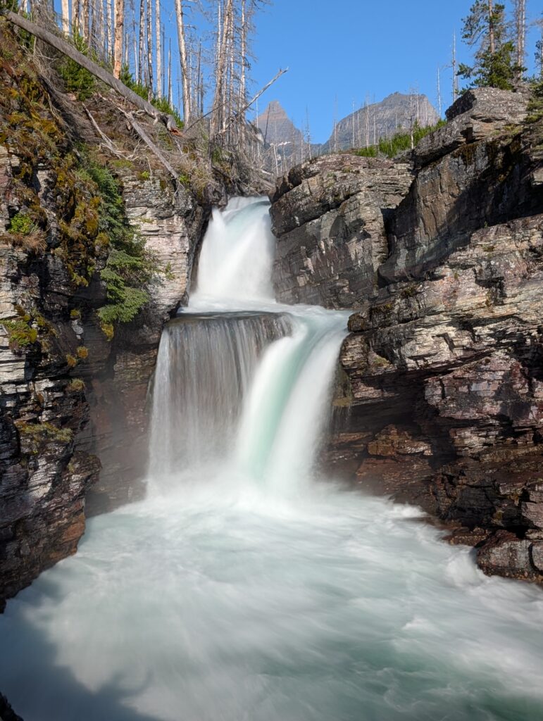 A two-tiered St. Mary Falls on a blue-sky day