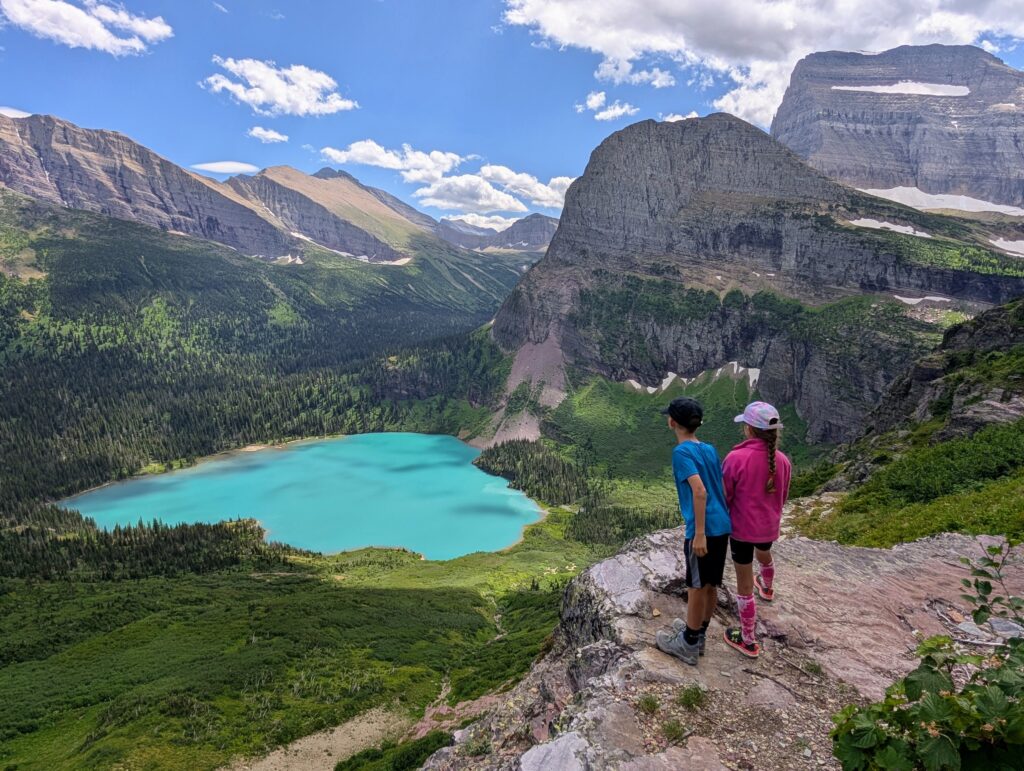 Young children high above a turquoise lake in Glacier National Park