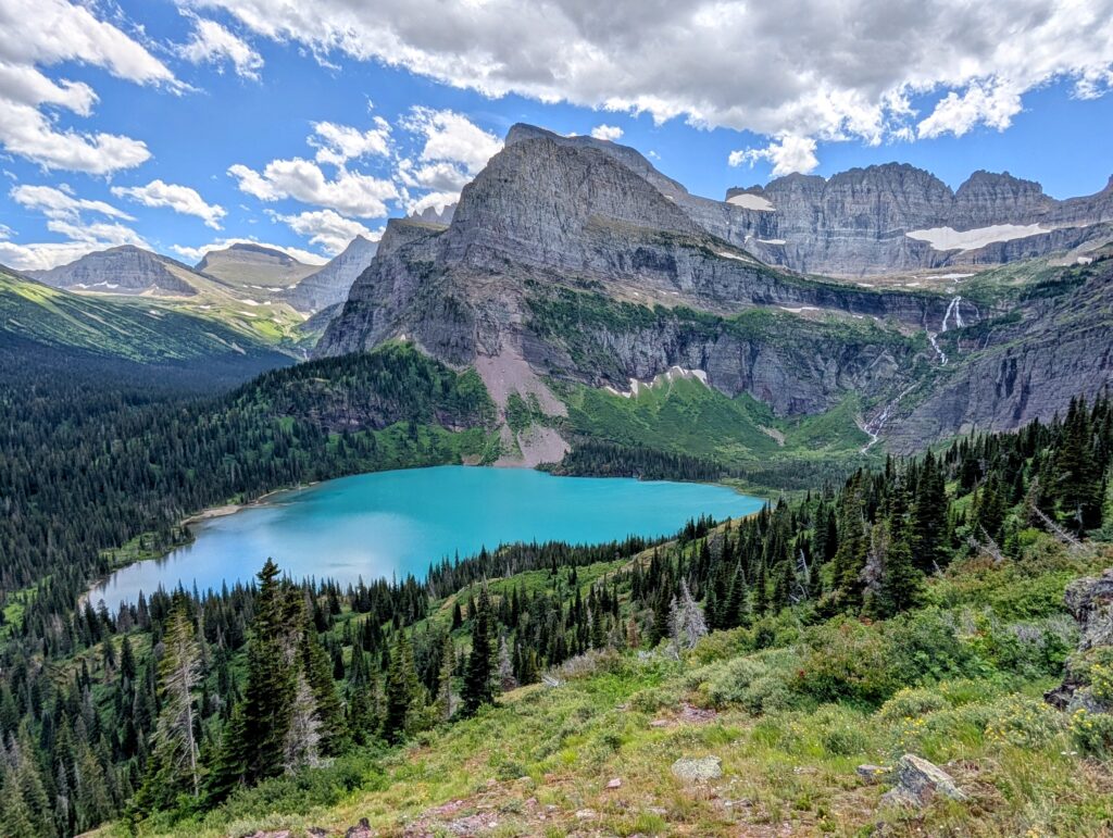 A teal-colored Grinnel Lake with a looming mountain over it in Glacier National Park
