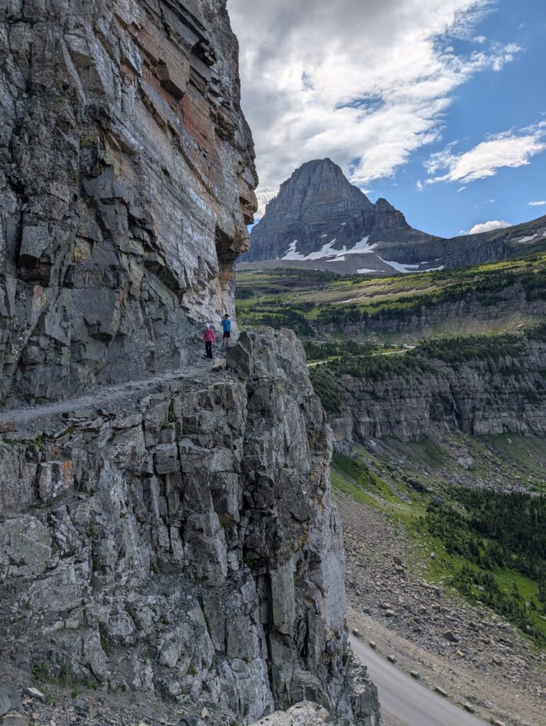 Two children along a rocky cliff-side trail in Glacier National Park