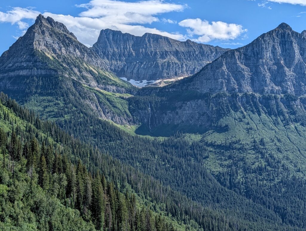 A thin waterfall surrounded by towering mountains along the Going to the Sun Road in Glacier National Park