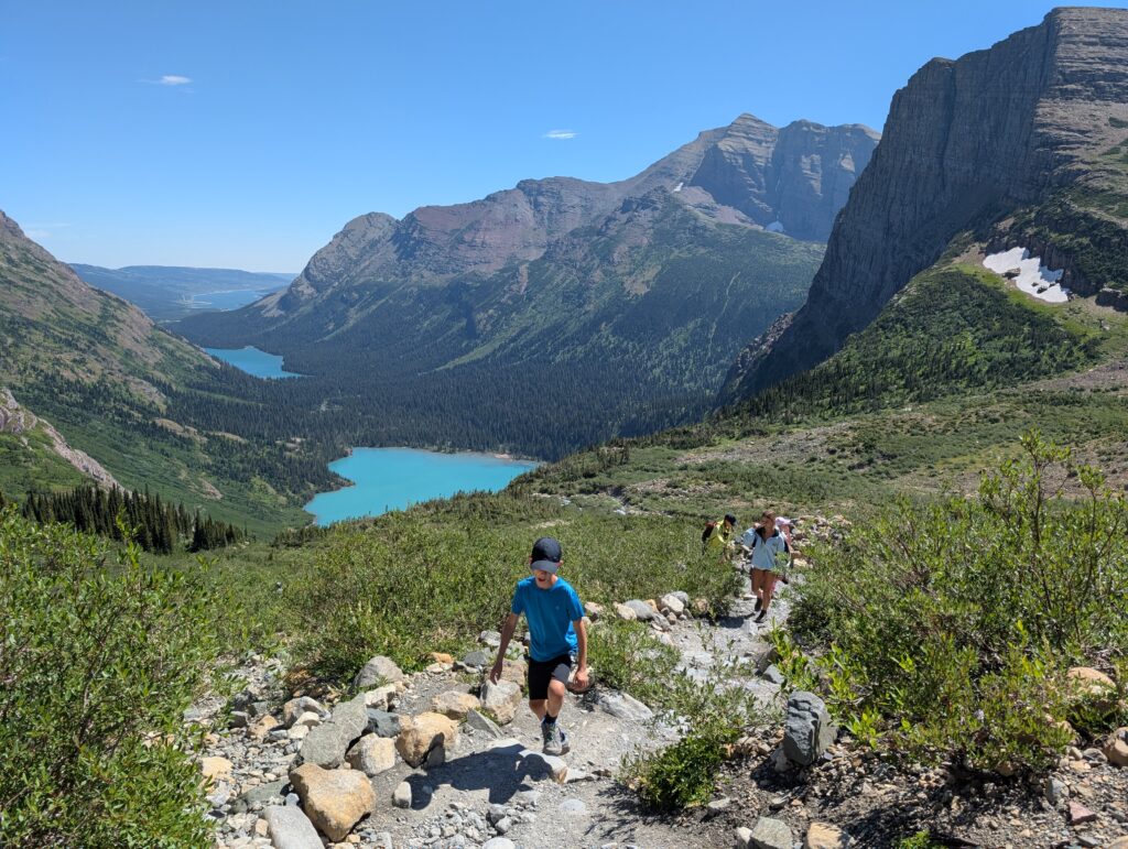Young hikers ascending a stone path with several lakes and mountains in the background