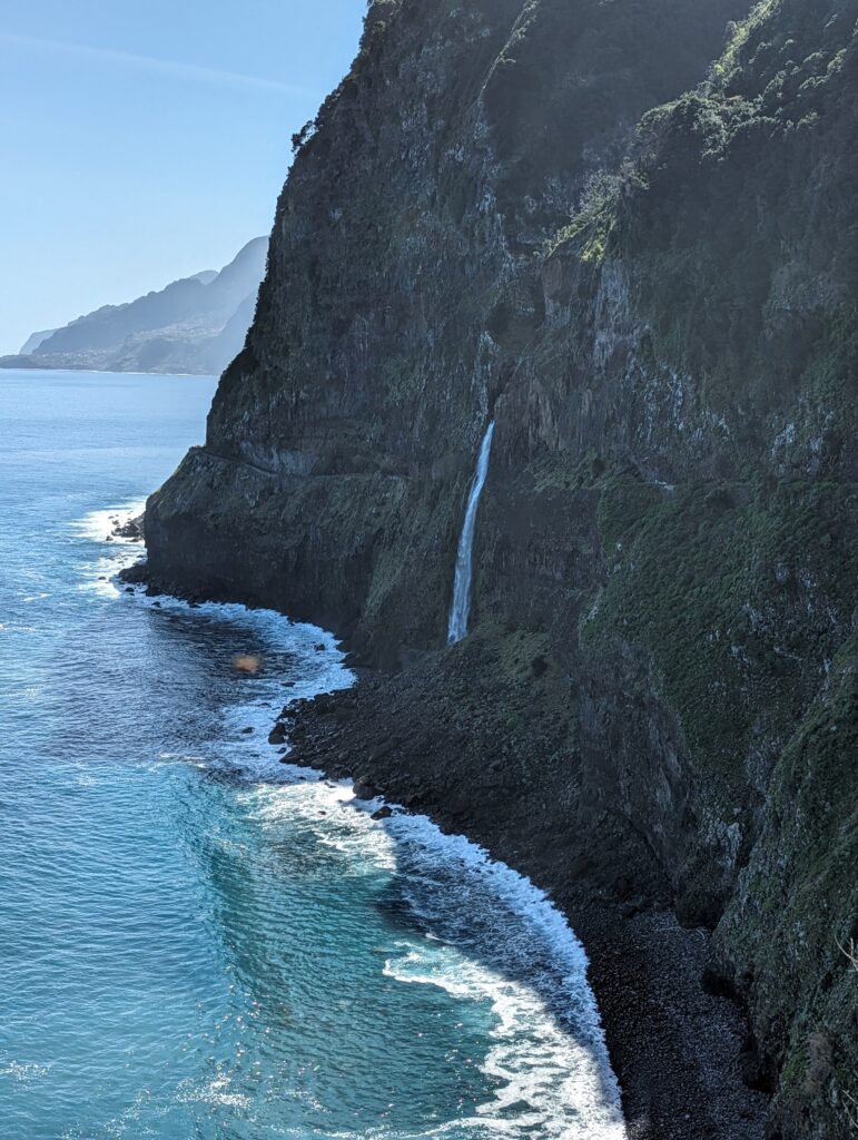 A waterfall jutting out of a cliffside straight down into the ocean