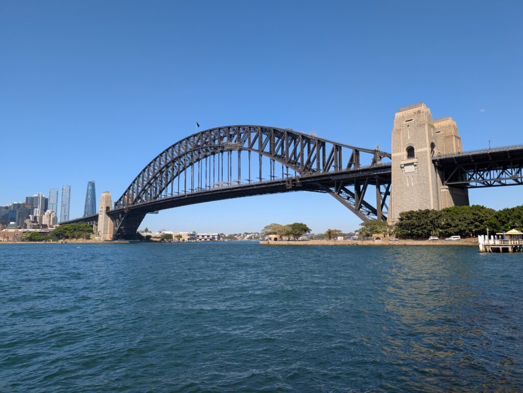 The entire Sydney Harbour Bridge with water in the foreground