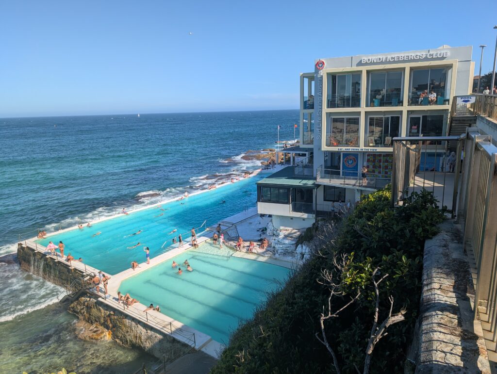 Two manmade pools of water right at the ocean's edge with a 4-story building right beside them