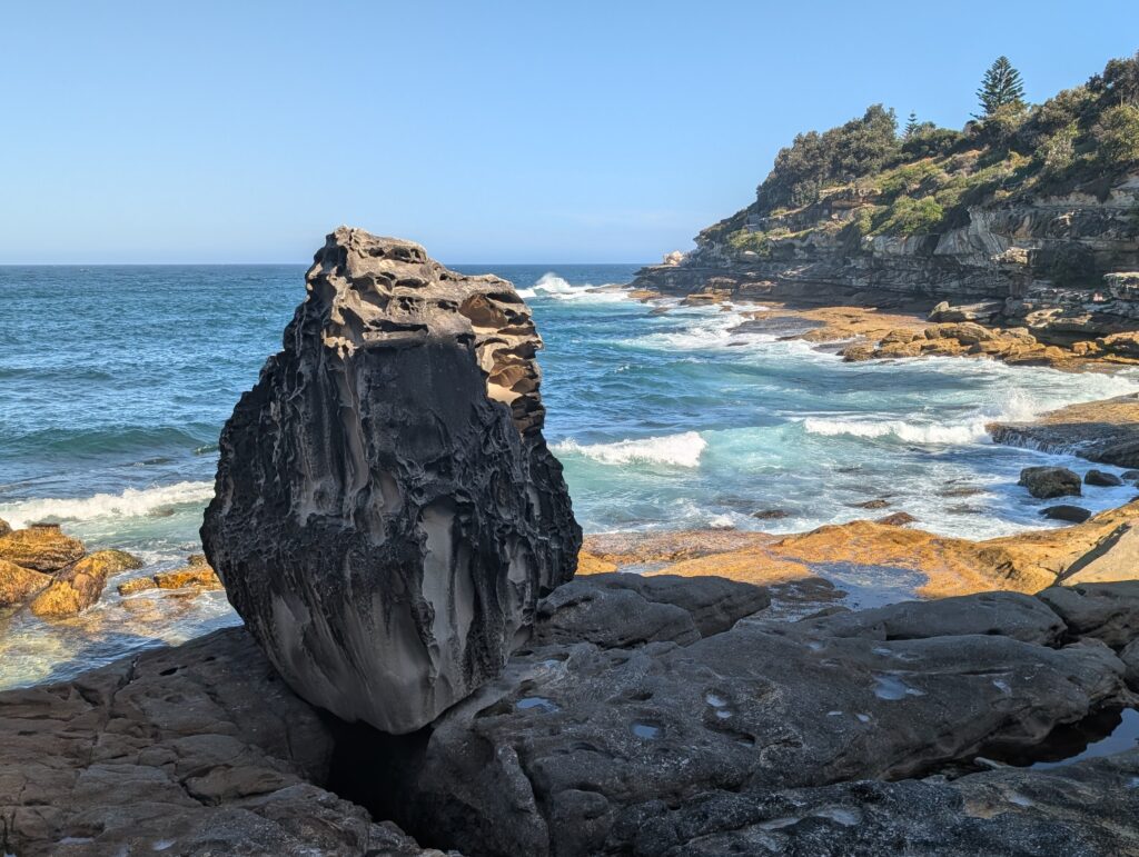 A vertical rock standing up along a rocky coast 