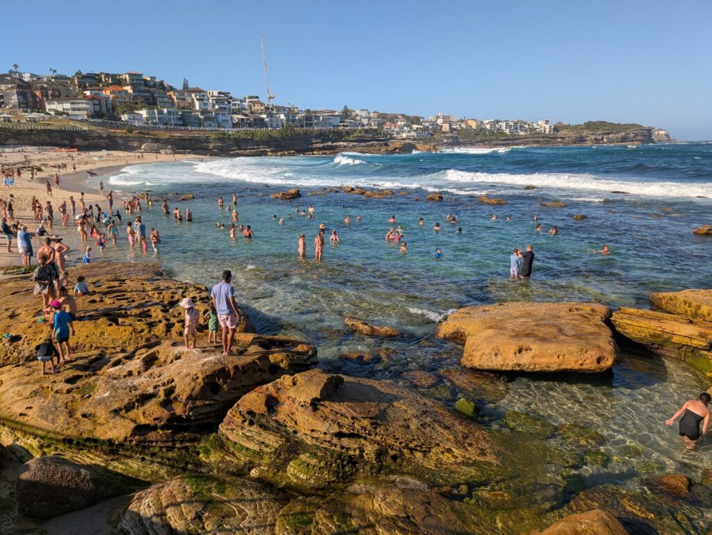 Many people in the water on a rocky beach