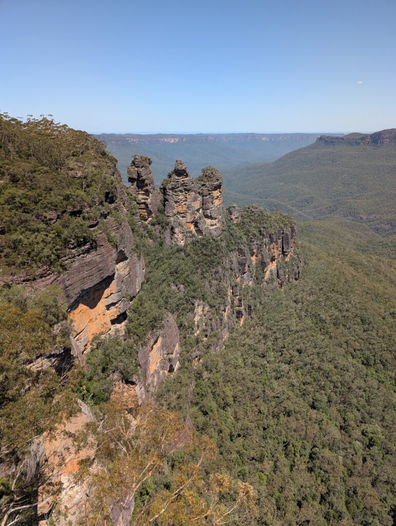 Three distinct rock formations sticking up on a green-covered rock wall