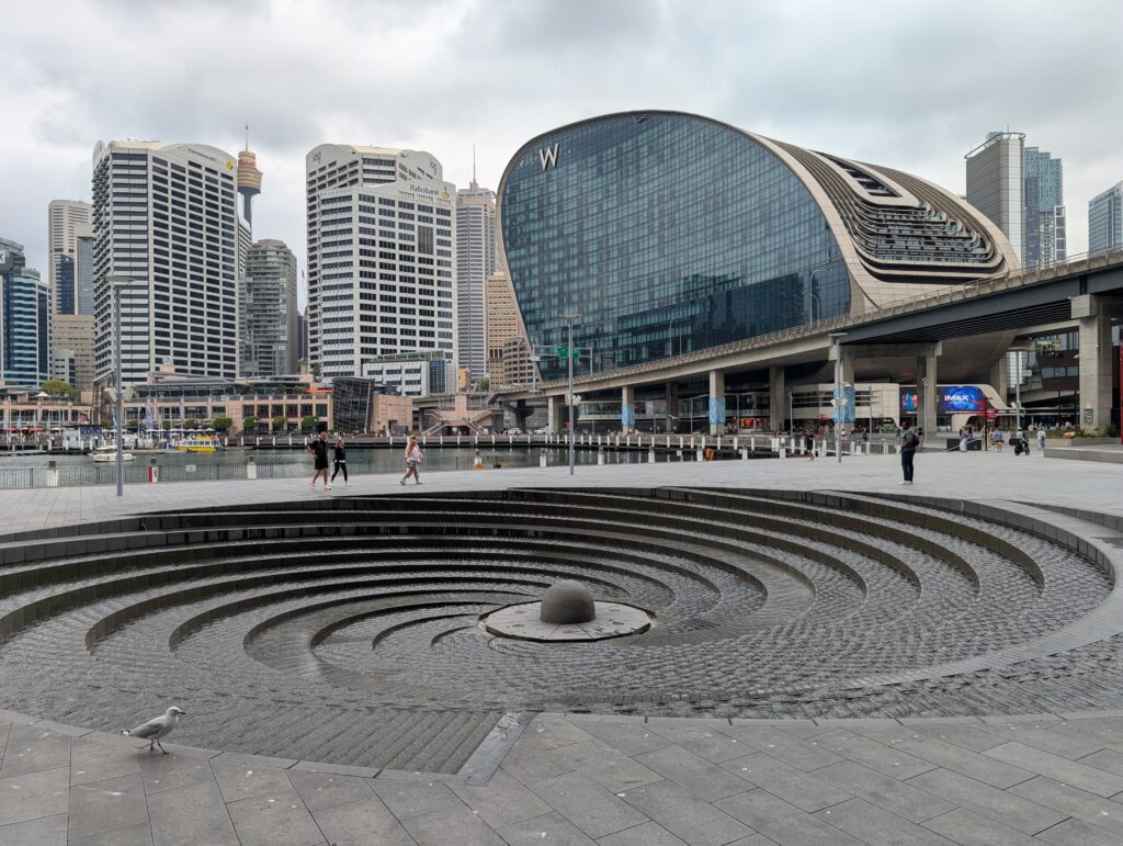 A spiral fountain in the foreground with the skyline of Sydney behind it