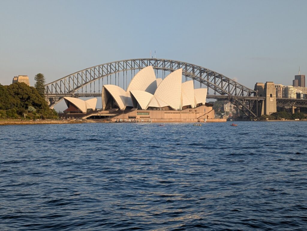 The Sydney Opera House centered in front of the Harbour Bridge