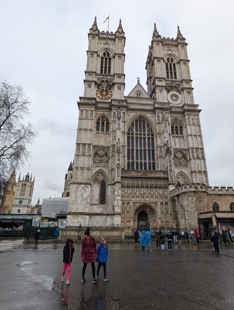 A family walking in front of a two-tower Westminster Abbey
