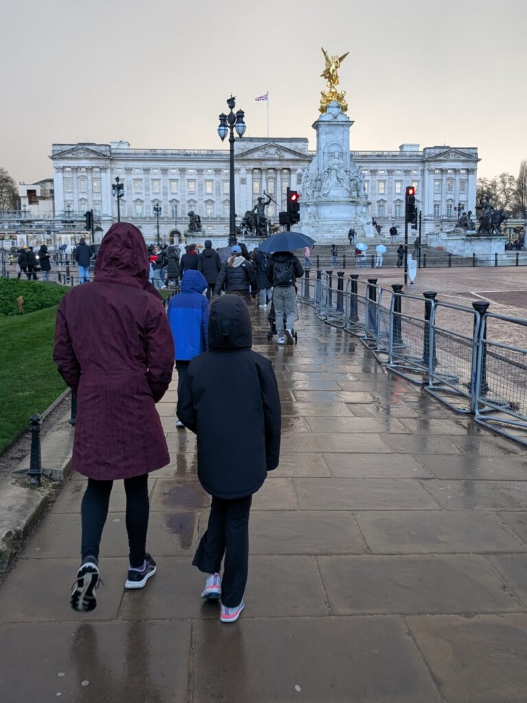 People walking towards Buckingham Palace on a gray day