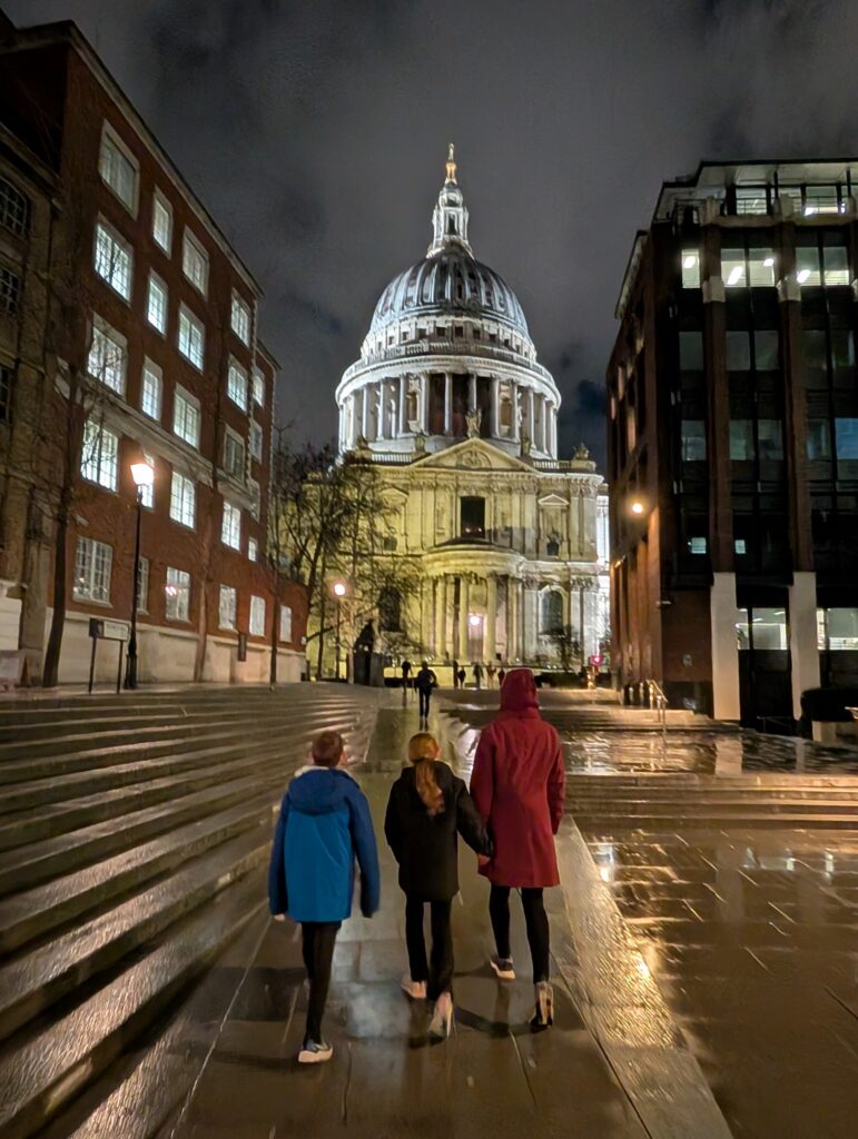 A mother and 2 children approaching St. Paul's Cathedral in London at night