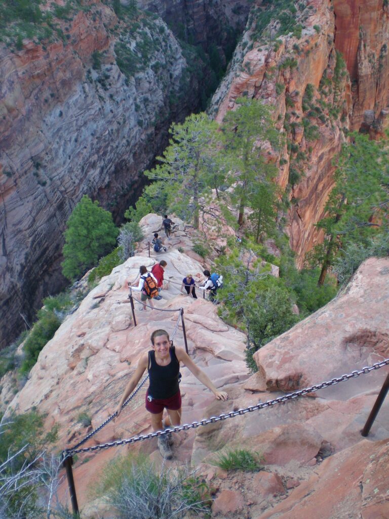 A woman on a steep, narrow hiking trail with chains