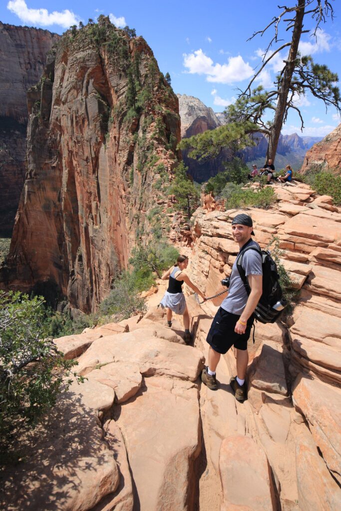 A man looking back while standing on a rocky trail with a large ridge in the background